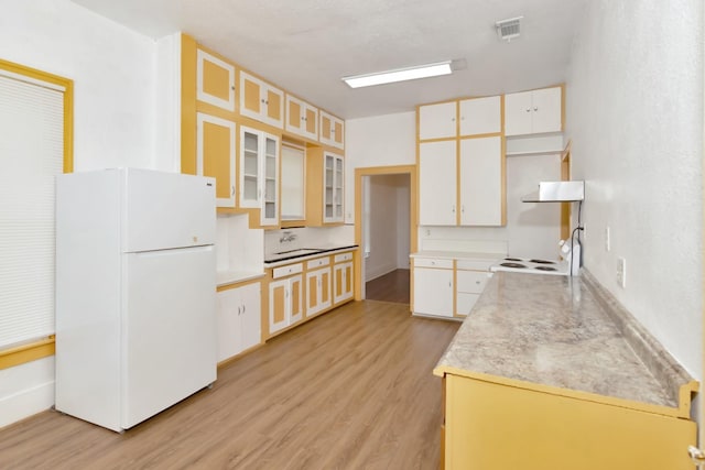 428 E Magnolia St, Angleton, TX 77515 - kitchen with light wood-style floors, glass insert cabinets, white appliances, visible vents, and under cabinet range hood