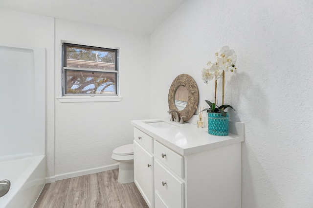 full bathroom featuring baseboards, toilet, a tub, vanity, and wood finished floors