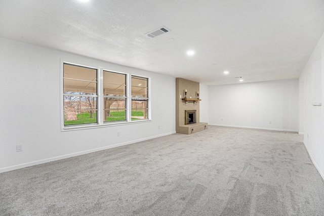 unfurnished living room with visible vents, recessed lighting, carpet flooring, and a brick fireplace