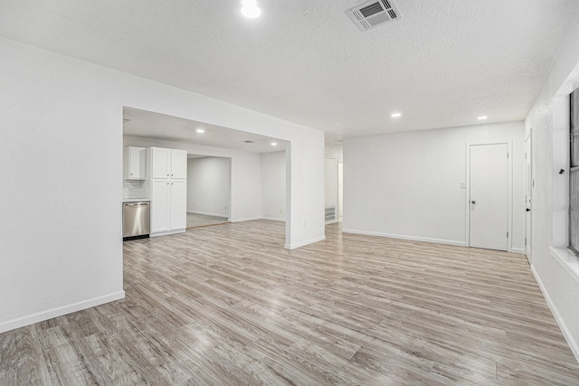 unfurnished living room with a textured ceiling, light wood finished floors, visible vents, and recessed lighting