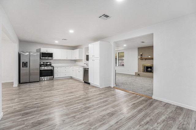 kitchen with open floor plan, visible vents, light wood-style floors, stainless steel appliances, and a sink