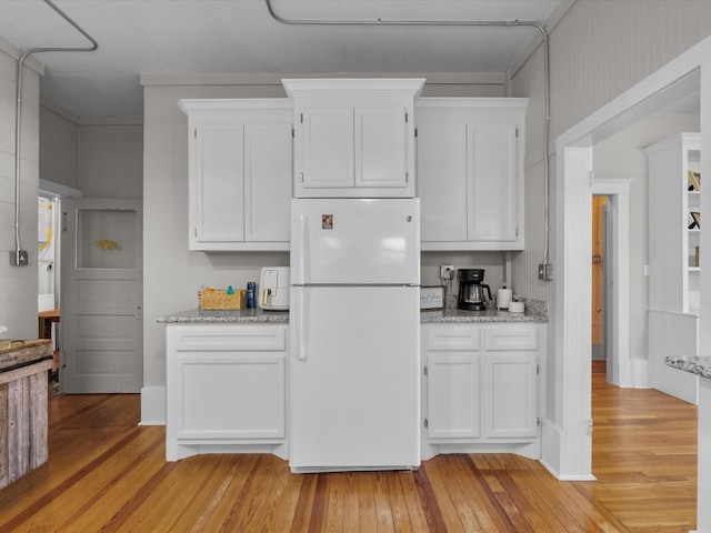602 W 1st St, Freeport, TX 77541 - kitchen featuring freestanding refrigerator, light wood finished floors, white cabinets, and light stone countertops