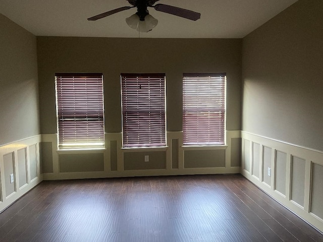 spare room with a ceiling fan, a decorative wall, wood finished floors, and a wainscoted wall