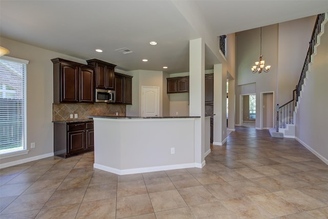 6103 Silver Thistle Ln, Fulshear, TX 77441 - kitchen featuring stainless steel microwave, tasteful backsplash, dark brown cabinetry, a chandelier, and light tile patterned floors