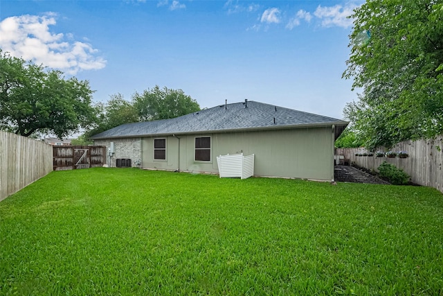 131 Breezy Shore Ct, Dickinson, TX 77539 - back of house featuring a lawn, a fenced backyard, central AC, and a shingled roof