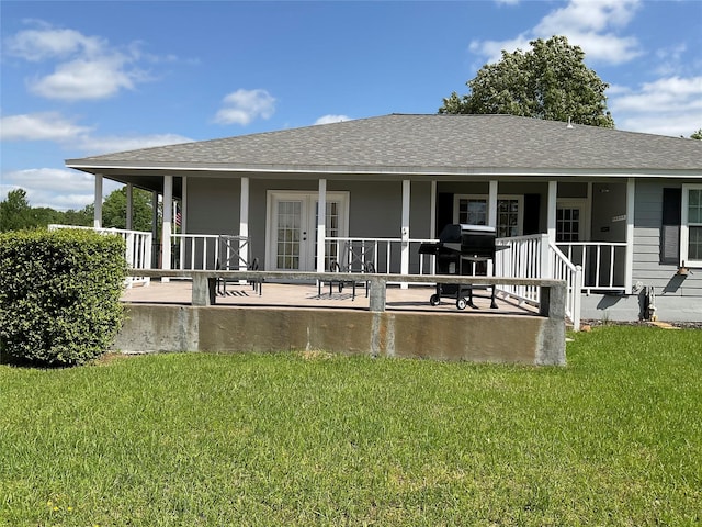 back of house with a yard, a shingled roof, and covered porch