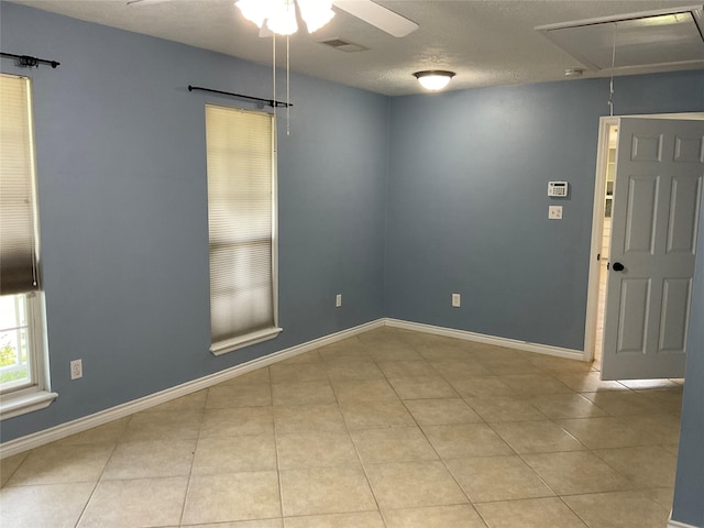 empty room featuring attic access, visible vents, a ceiling fan, and tile patterned flooring