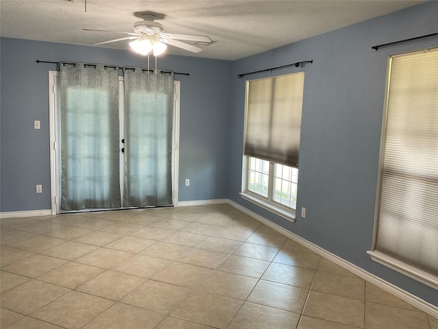 tiled spare room featuring a textured ceiling, baseboards, and ceiling fan