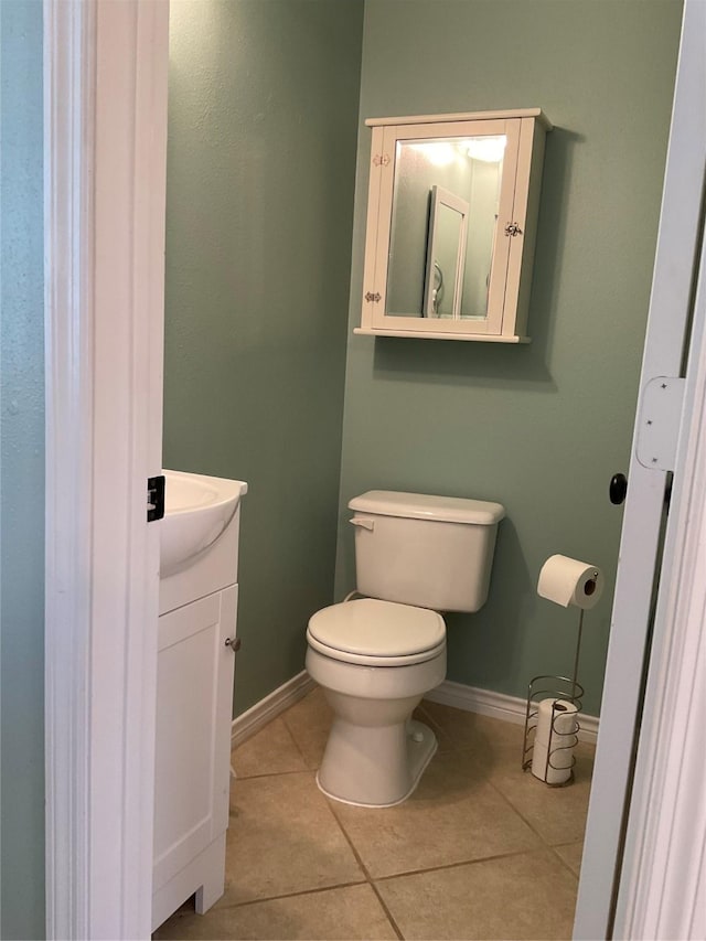 bathroom with toilet, vanity, baseboards, and tile patterned flooring