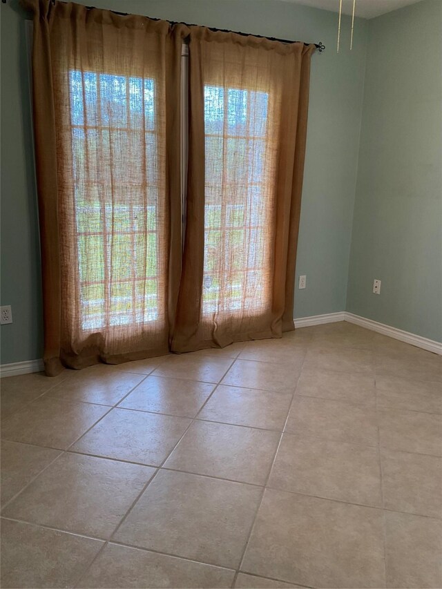 tiled empty room featuring baseboards