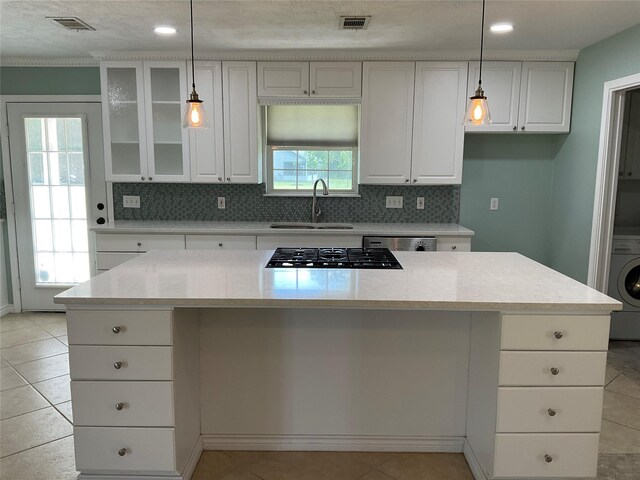 kitchen with tasteful backsplash, washer / clothes dryer, white cabinetry, and a sink