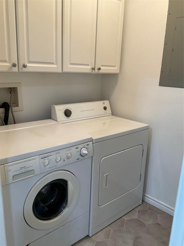 washroom featuring washer and clothes dryer, electric panel, light tile patterned floors, cabinet space, and baseboards
