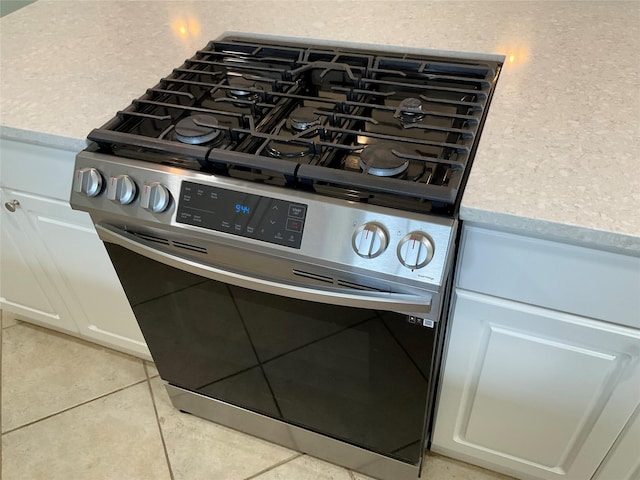 room details with white cabinets, light countertops, and gas stove