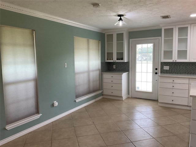 kitchen with white cabinets, decorative backsplash, visible vents, and light tile patterned floors