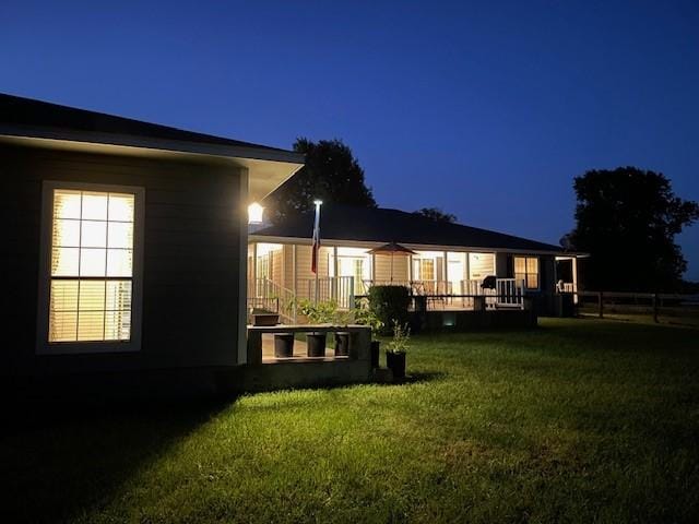 back of house at twilight featuring a yard