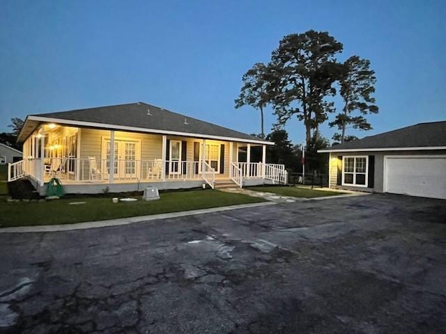 farmhouse inspired home with an attached garage, covered porch, and aphalt driveway