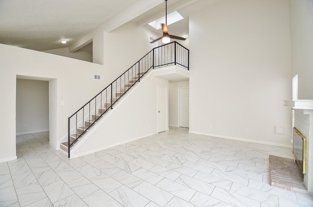 unfurnished living room featuring marble finish floor, high vaulted ceiling, and stairway