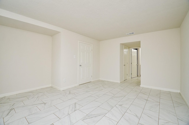 spare room featuring visible vents, marble finish floor, and baseboards