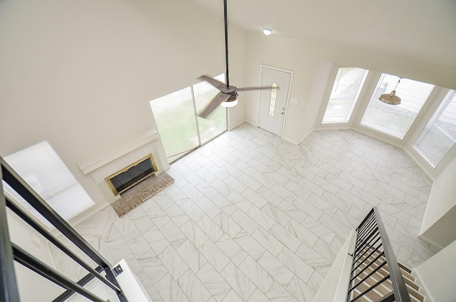 unfurnished living room featuring a ceiling fan and a brick fireplace