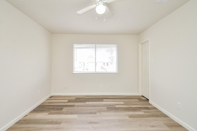 spare room featuring ceiling fan, baseboards, and light wood-style floors