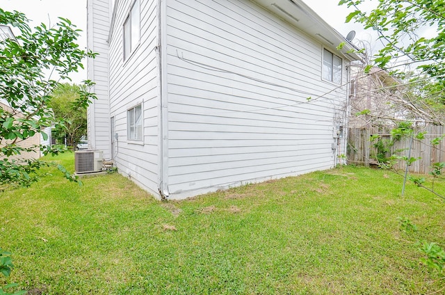 view of side of property with a lawn, fence, and cooling unit
