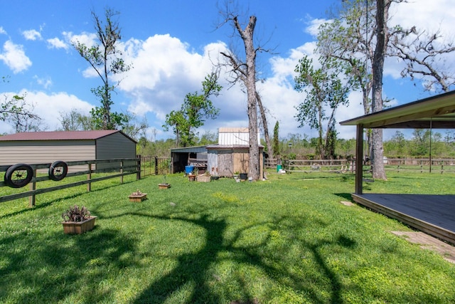 view of yard featuring fence, a wooden deck, and an outbuilding