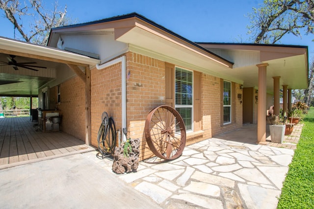 exterior space with a ceiling fan, brick siding, and a patio