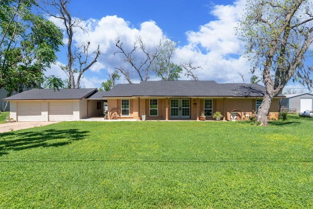 ranch-style house featuring concrete driveway, a front lawn, an attached garage, and french doors