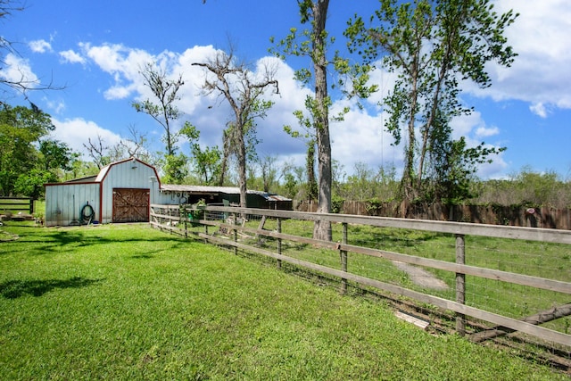 view of yard with an outdoor structure, a barn, a garage, and fence