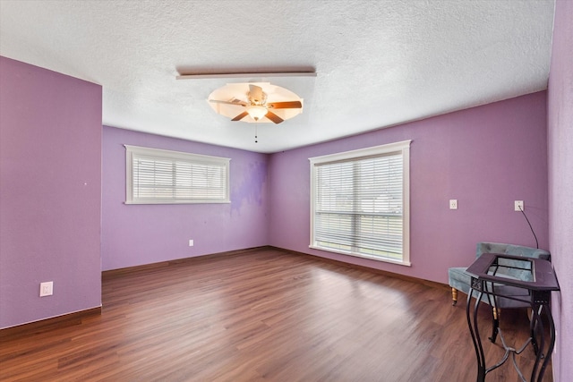 spare room featuring wood finished floors, a textured ceiling, and baseboards