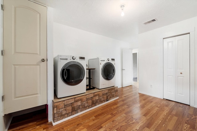 washroom with wood finished floors, visible vents, washer and dryer, and laundry area