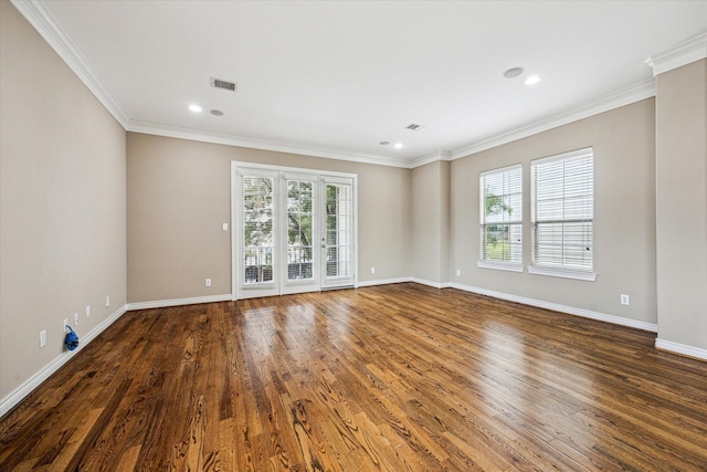 spare room with wood finished floors, visible vents, crown molding, and baseboards