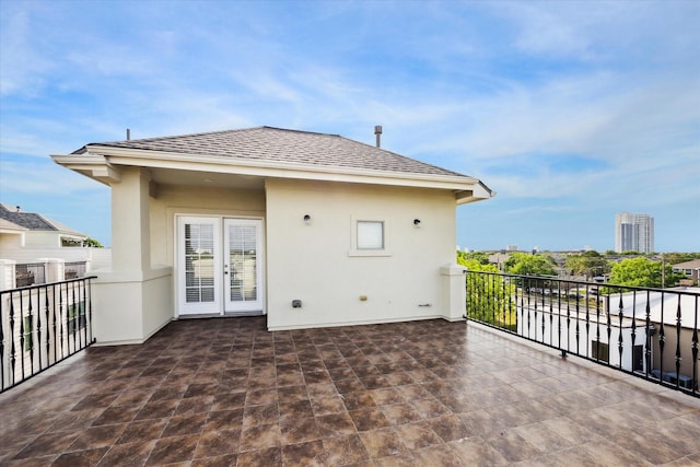 exterior space featuring a shingled roof, a balcony, and stucco siding