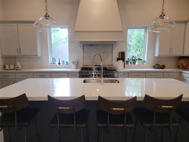 3714 Grennoch Ln, Houston, TX 77025 - kitchen featuring custom exhaust hood, backsplash, a kitchen bar, and hanging light fixtures