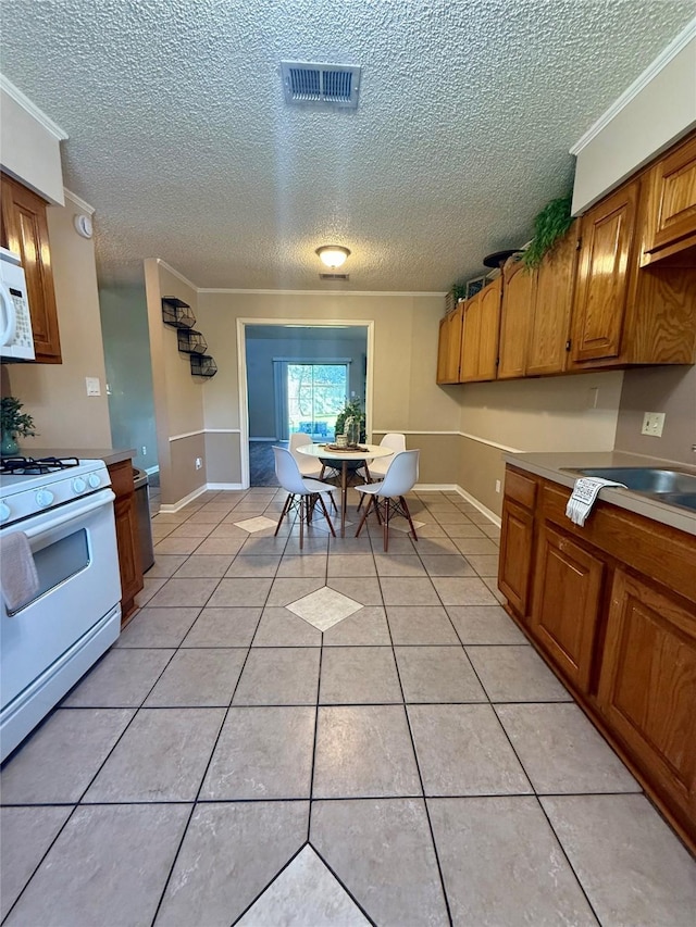 15 Murex St, Bay City, TX 77414 - kitchen featuring white appliances, ornamental molding, a textured ceiling, brown cabinetry, and light tile patterned floors