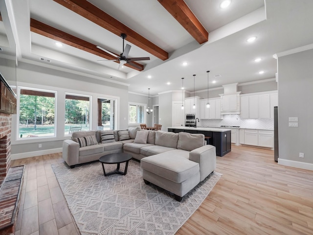 living area featuring a ceiling fan, baseboards, beam ceiling, and ornamental molding