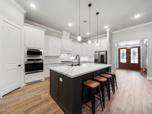 kitchen featuring a sink, appliances with stainless steel finishes, backsplash, ornamental molding, and visible vents