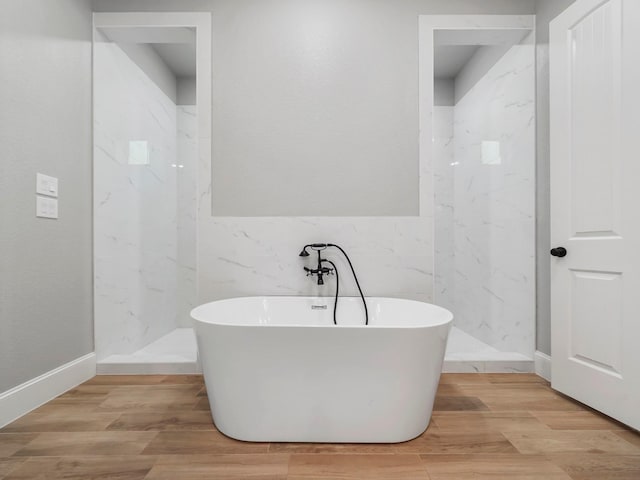 full bathroom featuring a soaking tub, tile walls, wood finished floors, and a marble finish shower