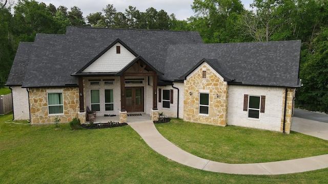 view of front of house featuring stone siding, a front yard, and french doors