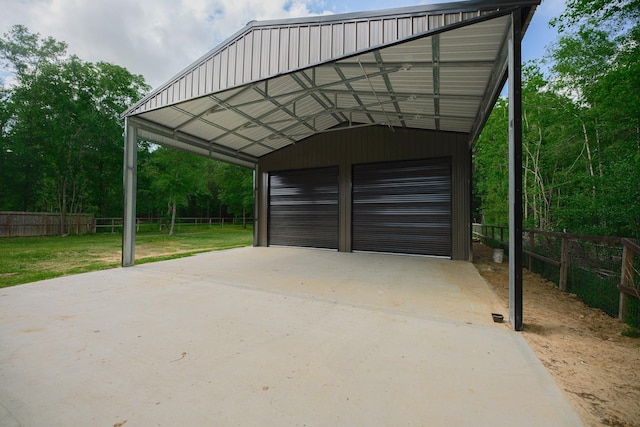 view of parking / parking lot featuring a detached garage and fence