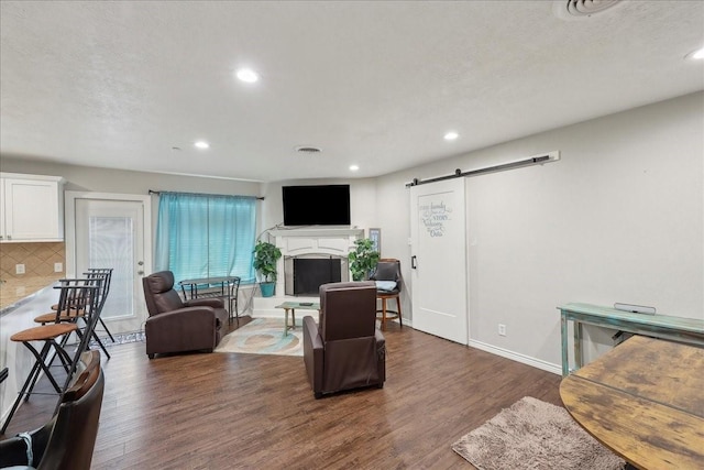 6360 Pansy Dr, Beaumont, TX 77706 - living area with baseboards, a fireplace with raised hearth, a barn door, dark wood-style floors, and recessed lighting