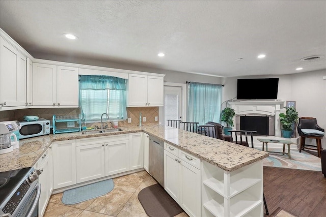 6360 Pansy Dr, Beaumont, TX 77706 - kitchen with white cabinets, open shelves, a sink, a peninsula, and stainless steel appliances