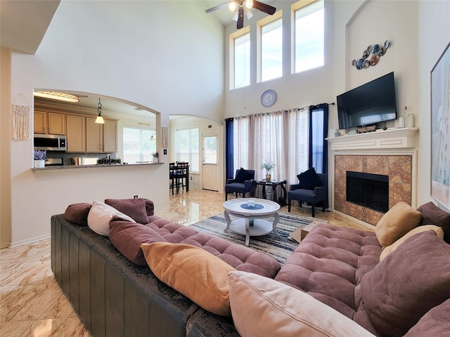 living room featuring ceiling fan, arched walkways, marble finish floor, and a towering ceiling