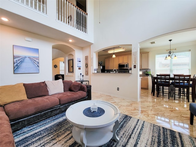 living area with arched walkways, a towering ceiling, recessed lighting, marble finish floor, and ornamental molding