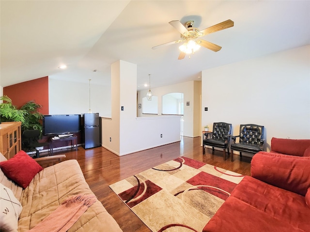 living area with vaulted ceiling, wood finished floors, arched walkways, and ceiling fan