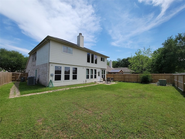 back of property with a fenced backyard, a chimney, a yard, and a patio