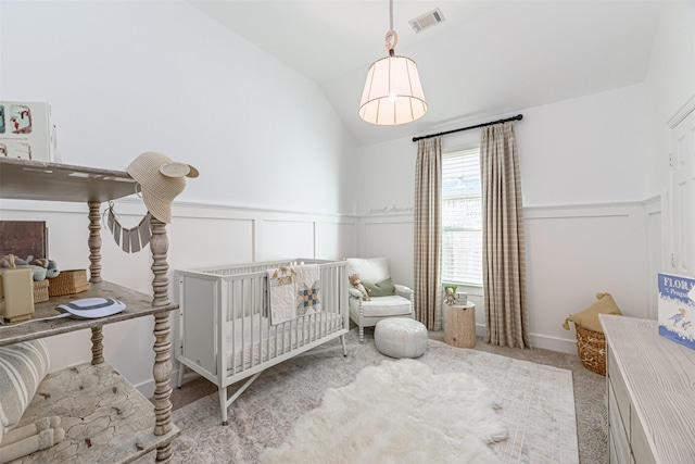 carpeted bedroom with a decorative wall, visible vents, a crib, and a wainscoted wall