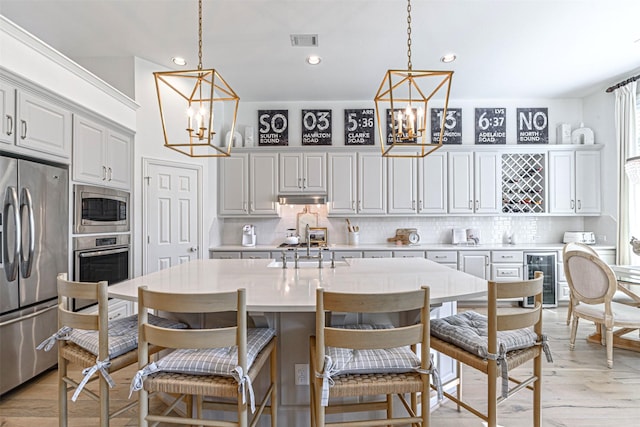 kitchen featuring stainless steel appliances, light countertops, a notable chandelier, and tasteful backsplash
