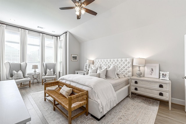 bedroom featuring baseboards, lofted ceiling, visible vents, and light wood-style flooring