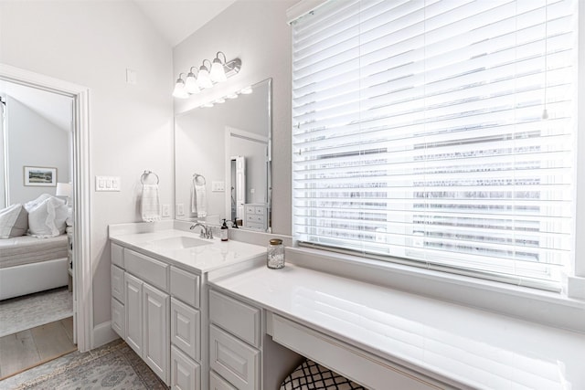 ensuite bathroom featuring vaulted ceiling, vanity, and ensuite bathroom